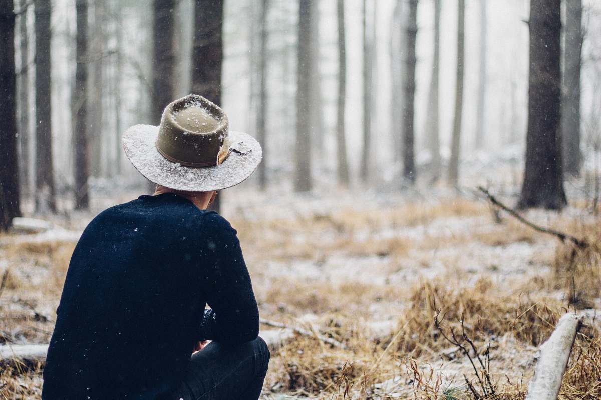 cowboy hat person sitting in grass field forest